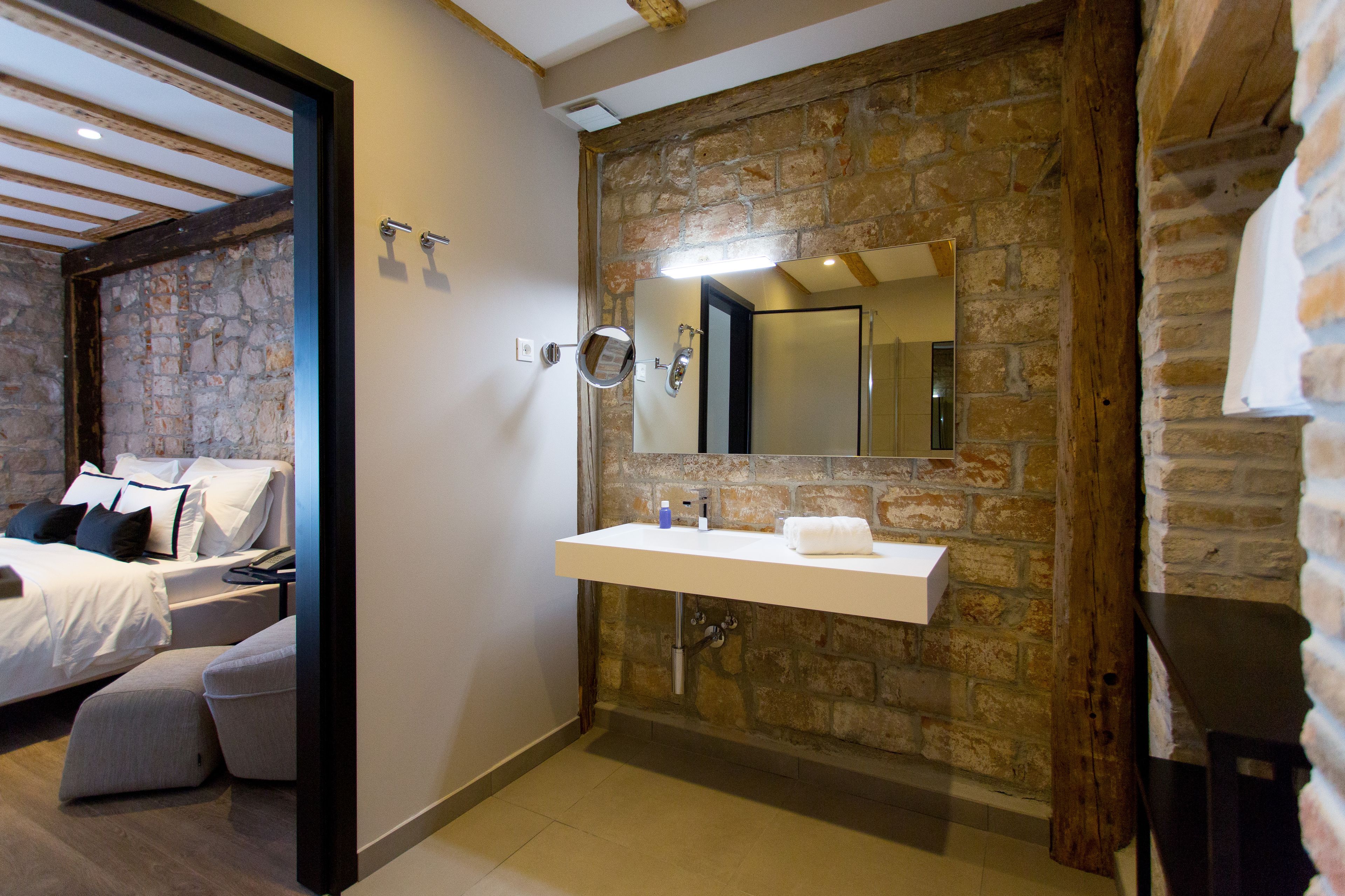 A modern bathroom with a stone wall, a white sink, and a mirror.