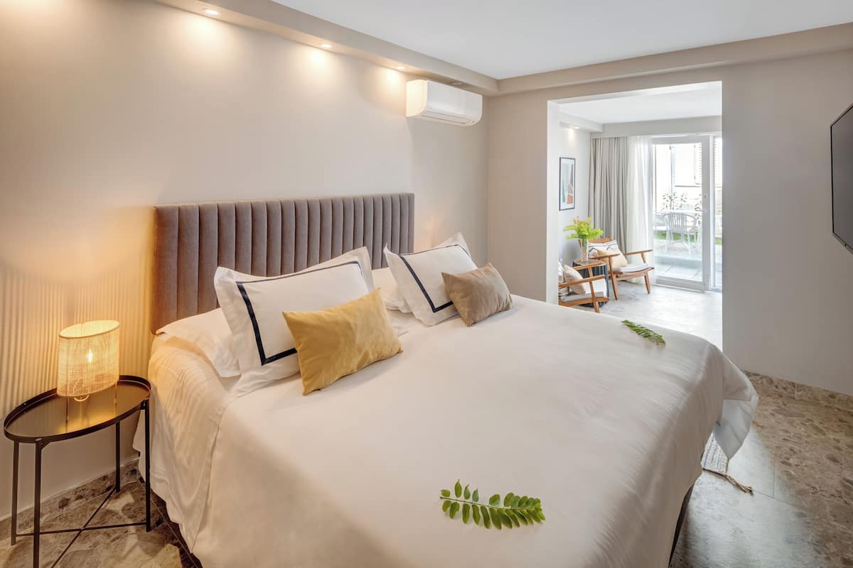 Habitación de hotel con una cama grande, una lámpara de noche y vistas al balcón.