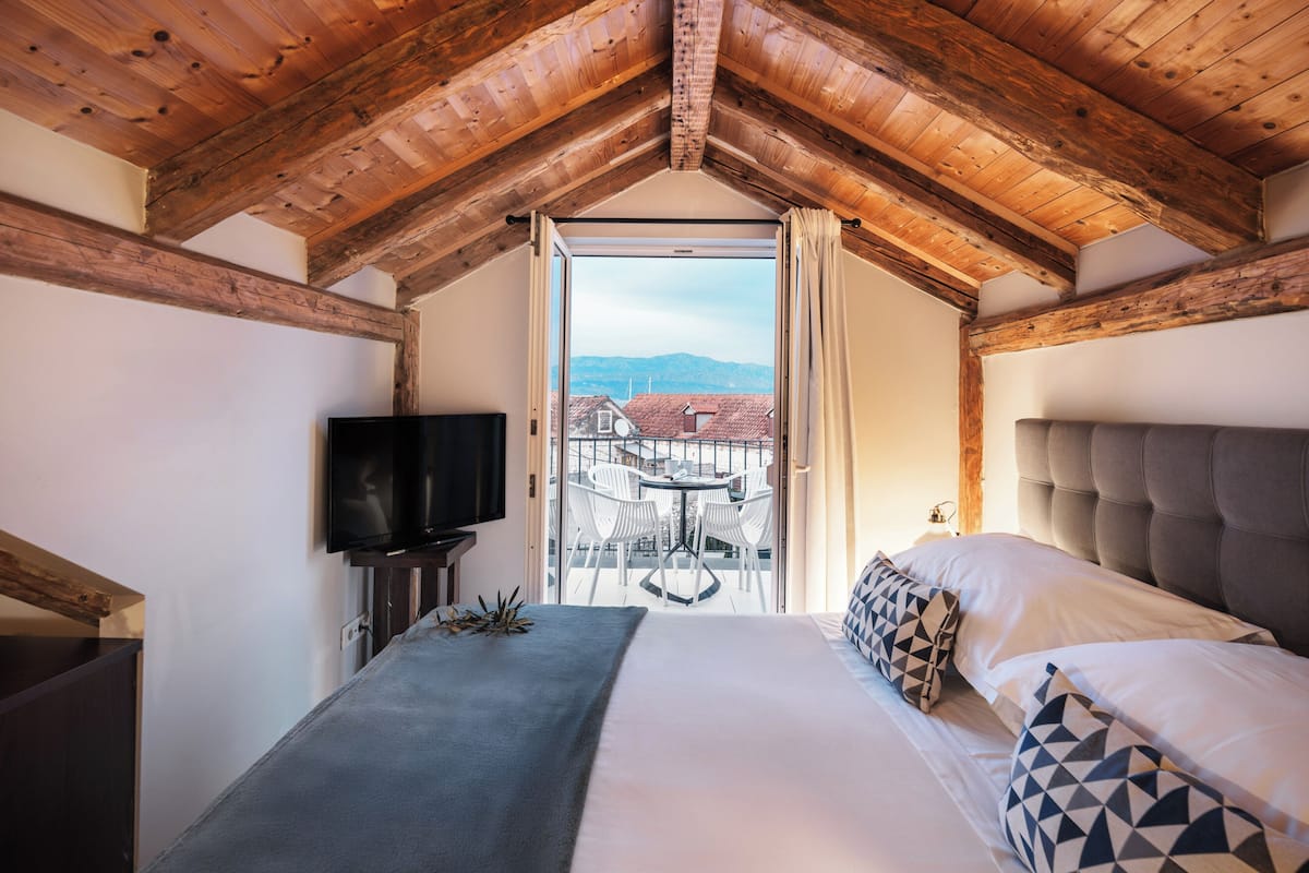 Un dormitorio con una cama grande, televisión y un balcón con mesa y sillas.