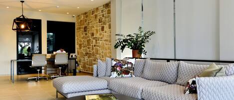 A modern living room with a sectional sofa, a coffee table, and a dining area with chairs and a table.