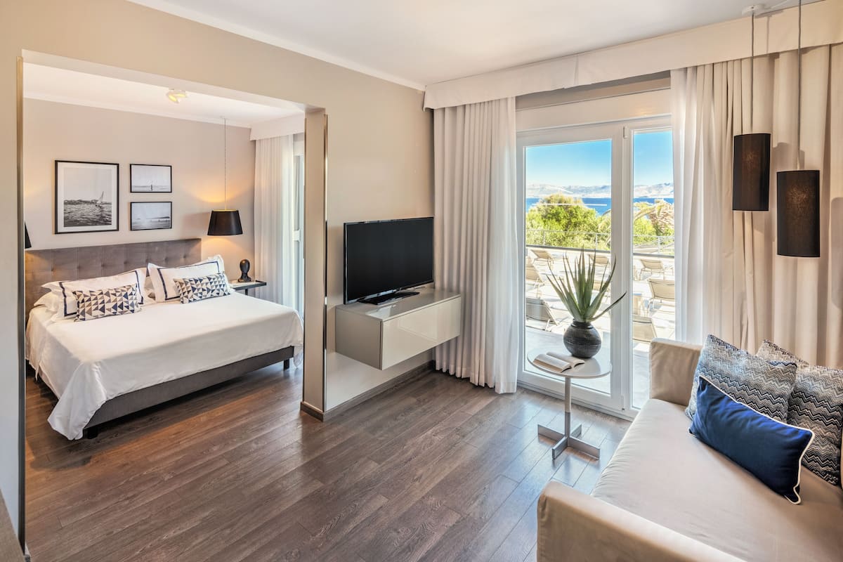 Una habitación de hotel moderna con cama, televisión, sofá y balcón con vistas.