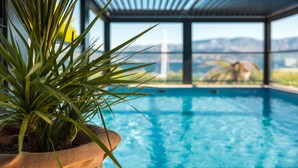 A pool with a view of mountains, a potted plant, and a pergola structure.