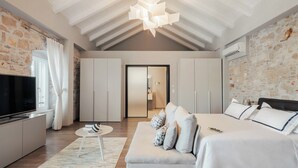 A modern bedroom with a large bed, a TV, and a stone wall.