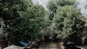 Un canal étroit où navigue un bateau, bordé d’arbres denses et de bâtiments.