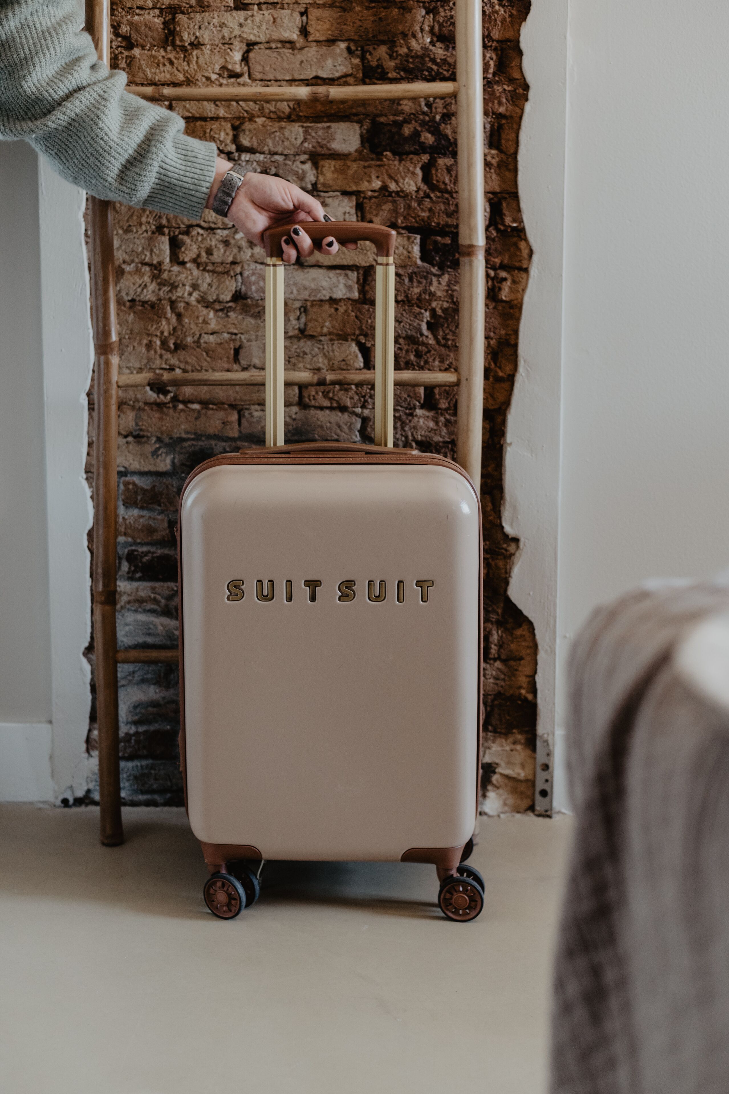 Une personne tirant une valise à roulettes avec une poignée.