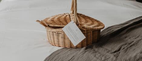 A neatly made bed with a wicker basket on it, a brick wall, and two lamps in the background.