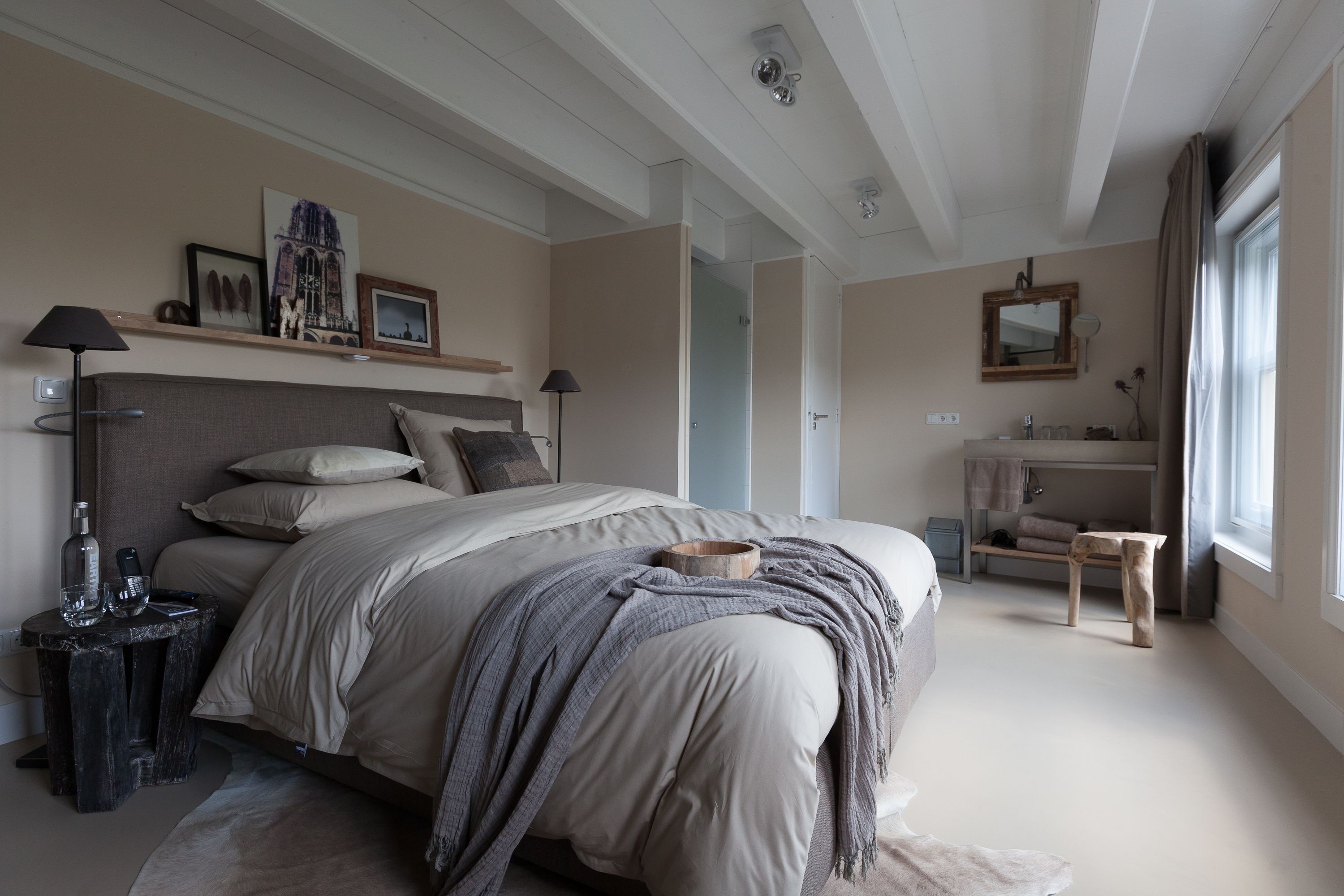 A bedroom with a large bed, bedside tables, a nightstand, a dresser, a mirror, and a window with curtains.