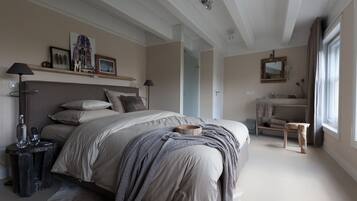 A bedroom with a large bed, bedside tables, a nightstand, a dresser, a mirror, and a window with curtains.