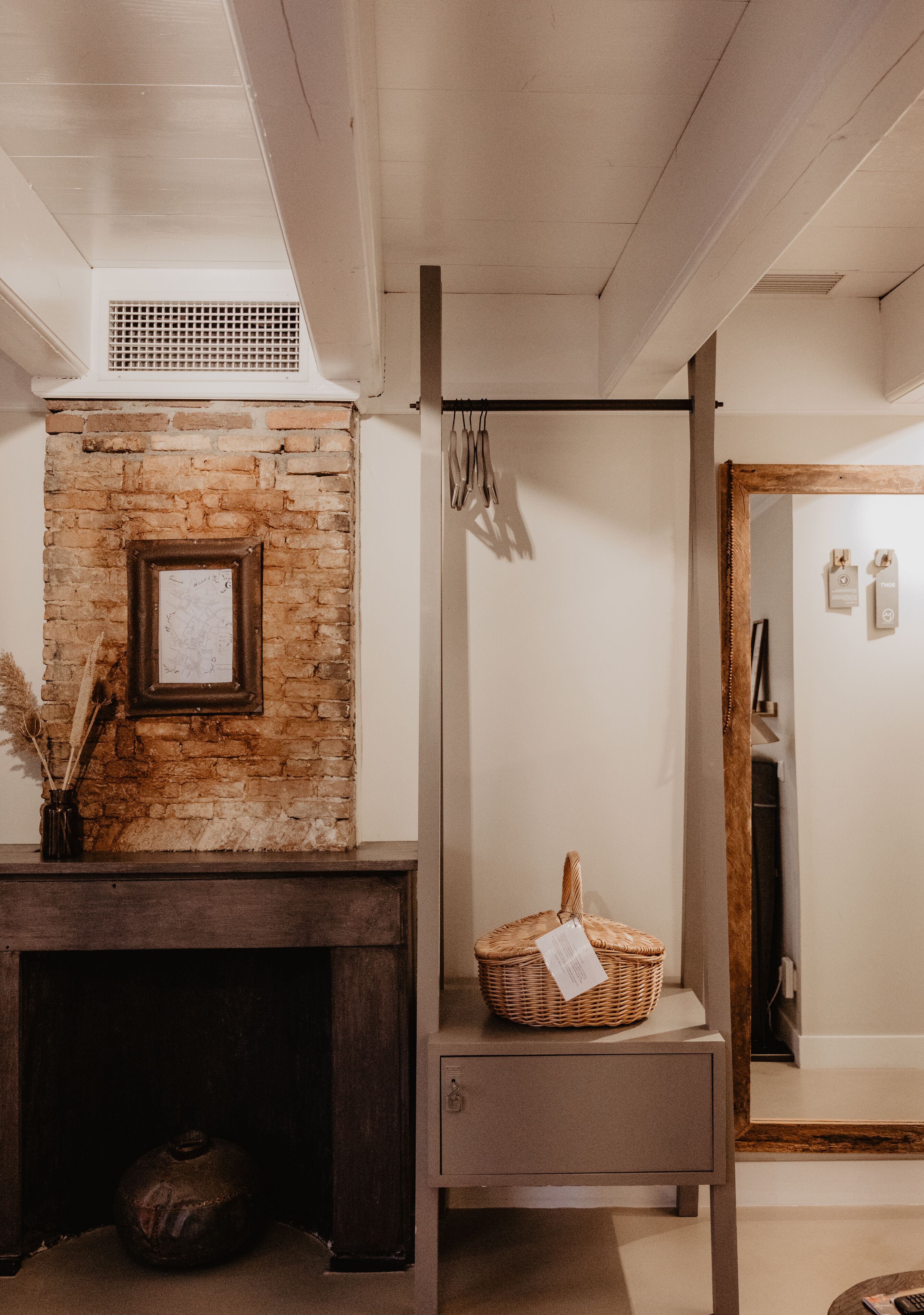 Een kamer met een bakstenen muur, een lijst met foto, een mand en een houten kast.