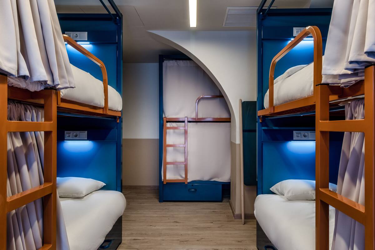 A room with bunk beds, a ladder, and a blue wall.