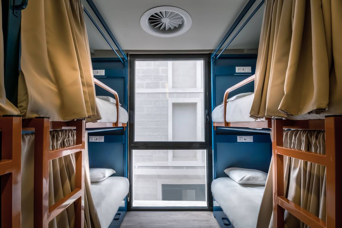 A compact room with bunk beds, a window, and a ceiling vent.
