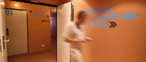 A corridor with a sign indicating the location of showers, laundry, and kitchen facilities.