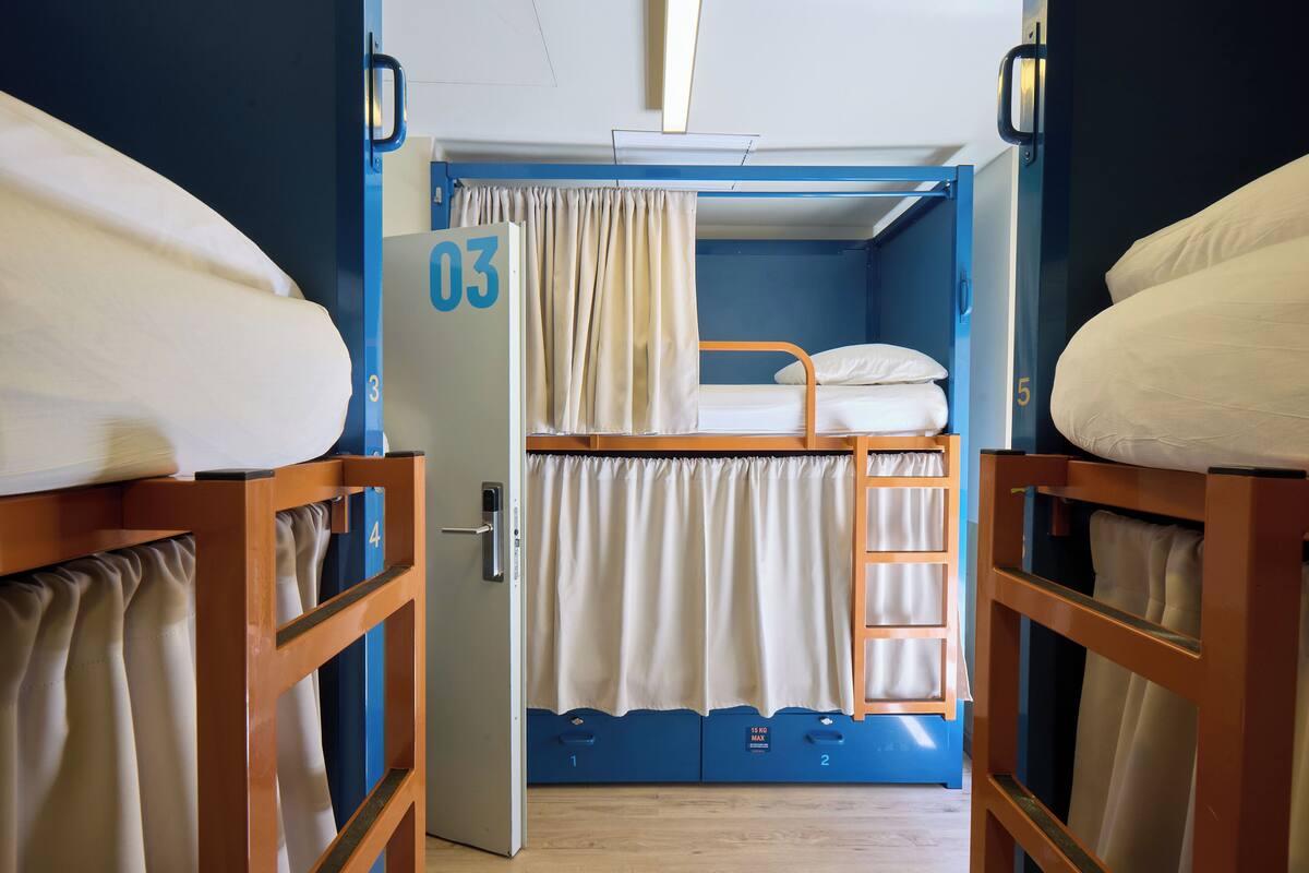 A bunk room with a bunk bed, a curtain, and a ladder.