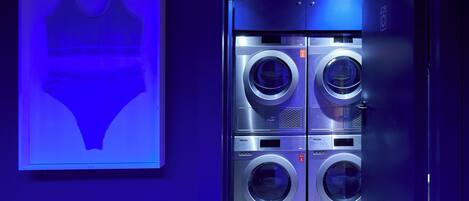 A modern, well-lit laundry room with four stacked front-loading washing machines.