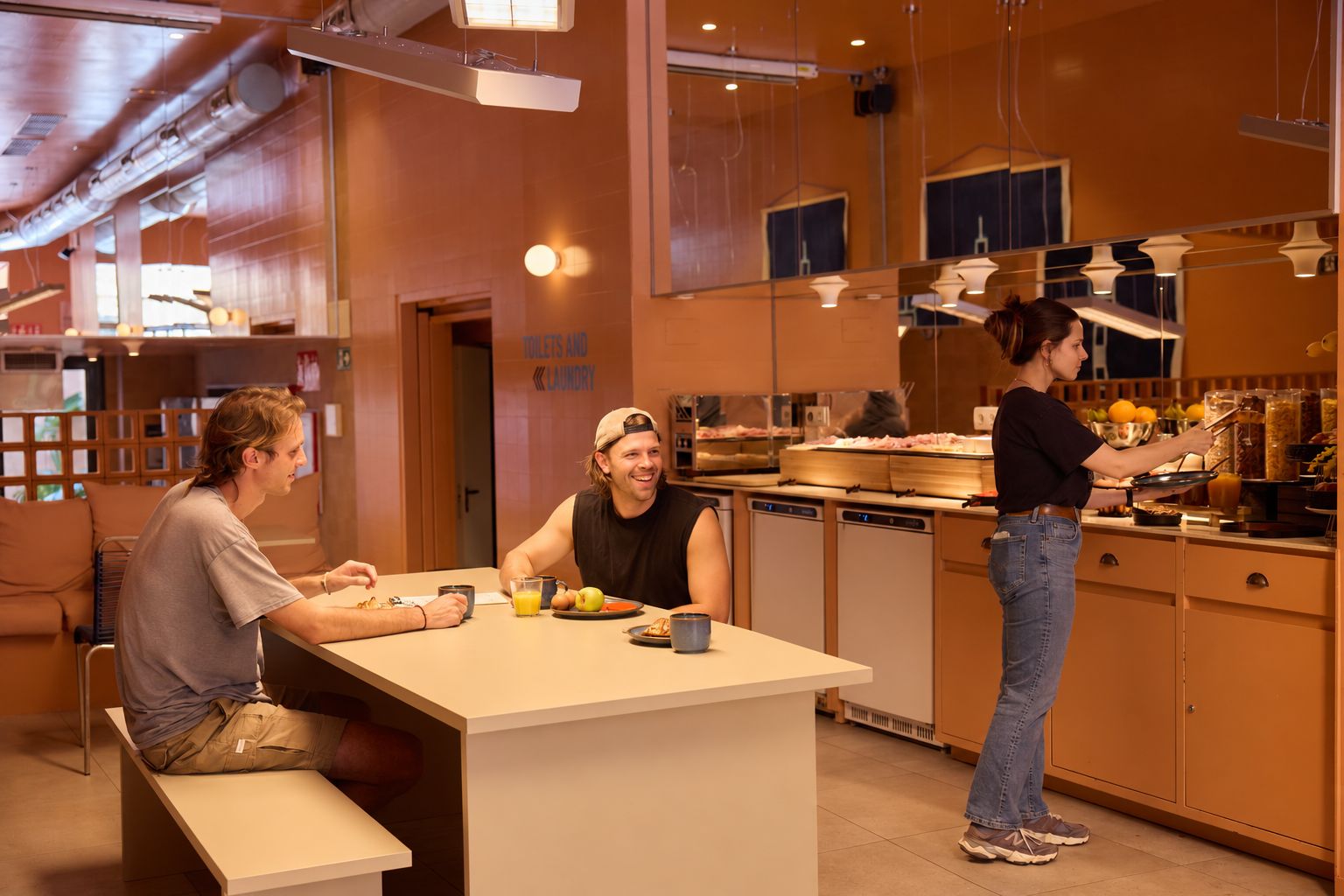 A breakfast area with a counter, seating, and a person serving food.