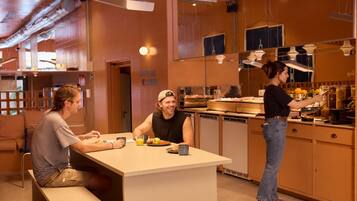 A breakfast area with a counter, seating, and a person serving food.
