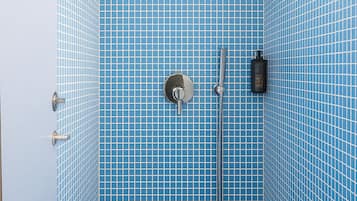 Un baño pequeño con azulejos, suelo y paredes azules, un cabezal de ducha manual, un grifo empotrado y un dispensador de jabón.