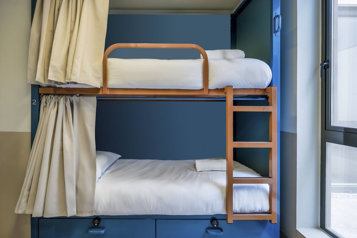 A bunk bed with a ladder, a window, and curtains.