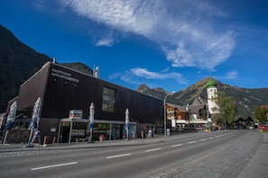 A modern building labeled "GASTAUER APARTMENTS" with a restaurant and outdoor seating.