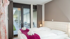 Une chambre d’hôtel avec un grand lit, une table de chevet, une fenêtre avec des rideaux et une vue sur l’extérieur.