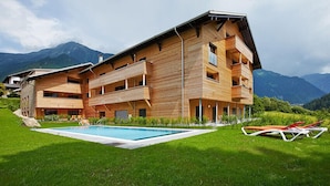 Un bâtiment en bois à plusieurs étages, doté d’une piscine et de chaises longues.