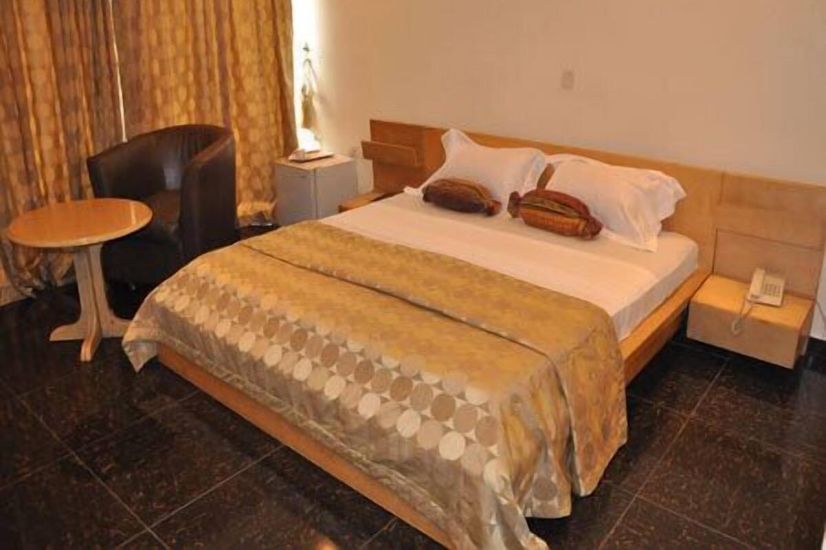 Une chambre d’hôtel avec un lit, une table de chevet, une chaise et une petite table.