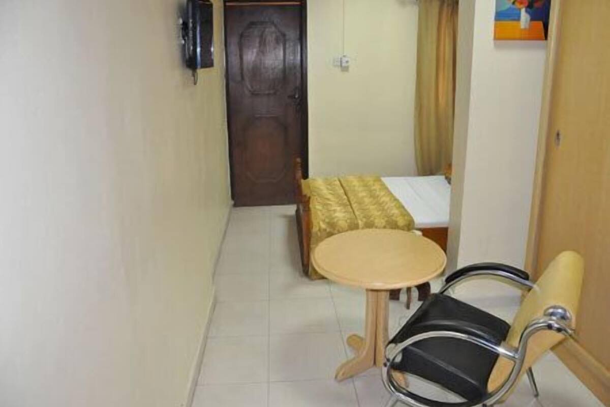 Une petite pièce avec un lit, une chaise, une table et une porte.