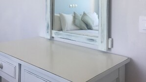 A white vanity with a mirror, a light switch, and a power outlet on the wall. - Ilena Hotel (Corfu)