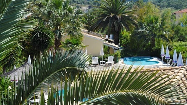 A pool area with palm trees, lounge chairs, and umbrellas. - Ilena Hotel (Corfu)