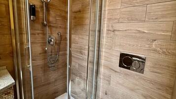 Une cabine de douche avec une porte en verre, des toilettes avec un abattant et un porte-serviettes fixé au mur.