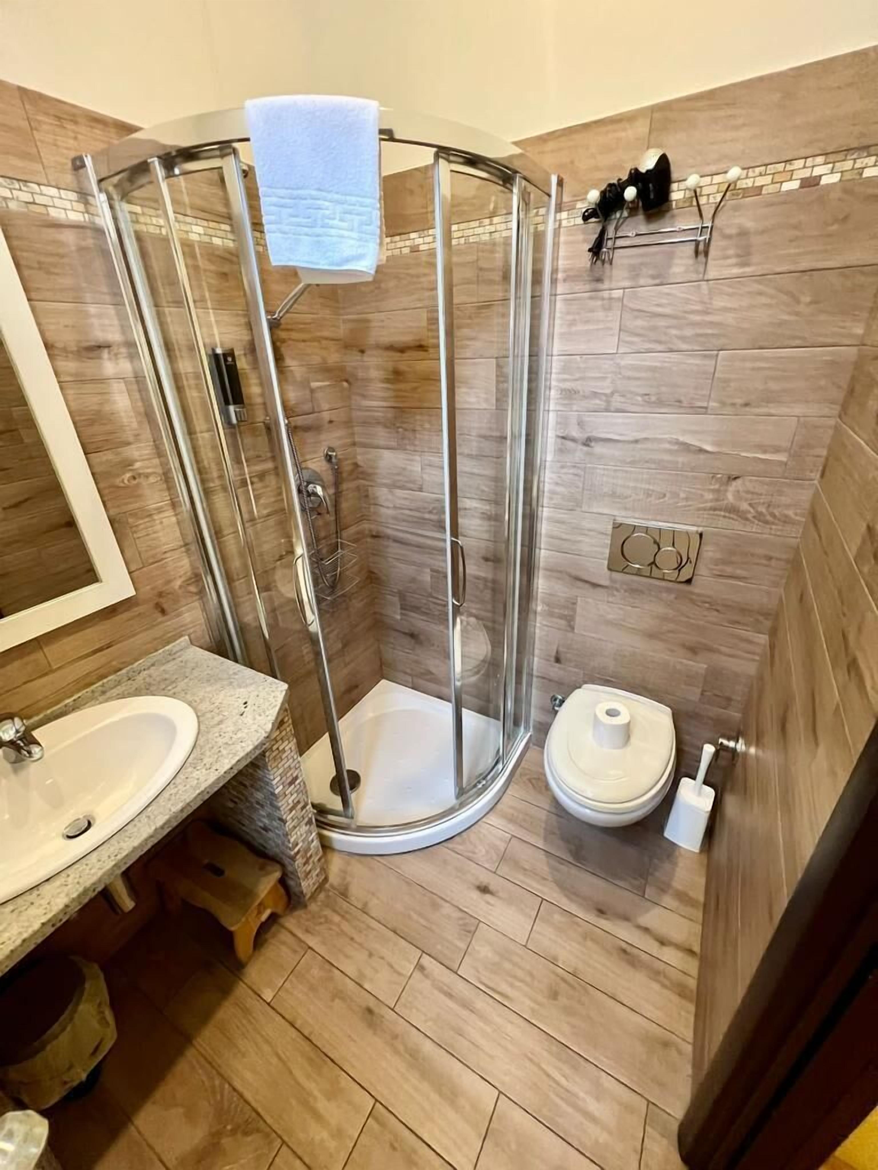 A modern bathroom with a glass-enclosed shower, a sink, and a toilet.