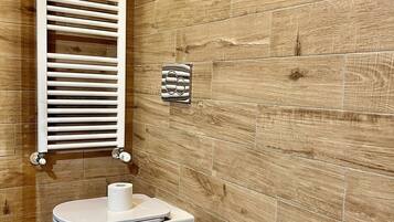 A bathroom with a wooden wall, a white towel rack, a bidet, and a sink.