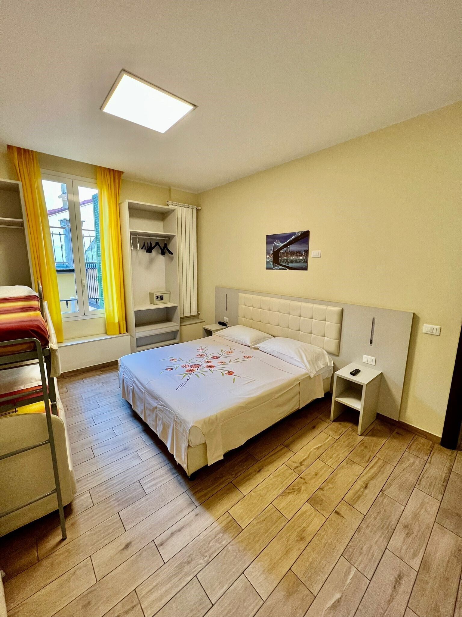 Habitación de hotel con cama, mesita de noche, armario y ventana con cortinas.