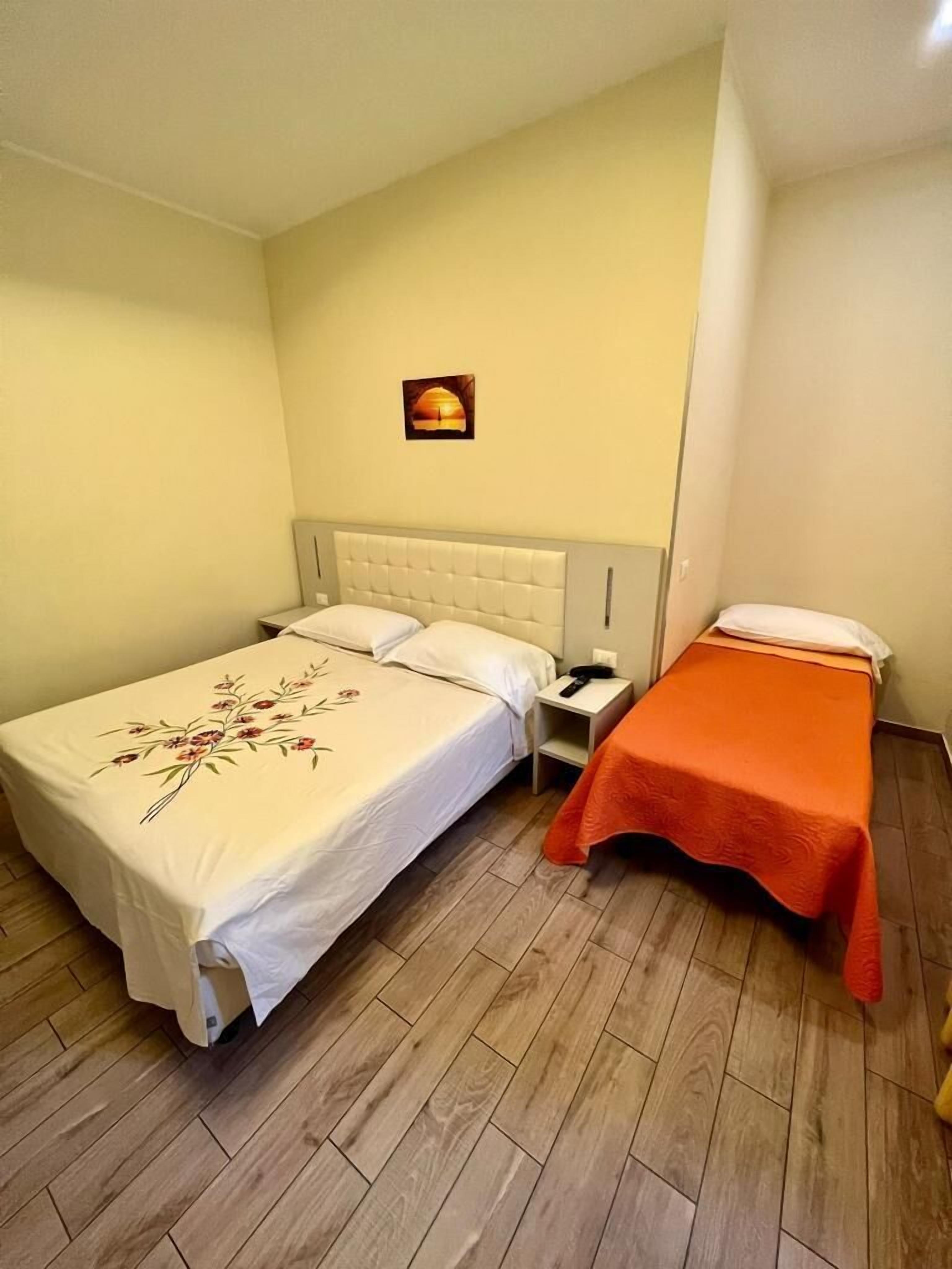 A room with a bed, a nightstand, and a small table with a chair.