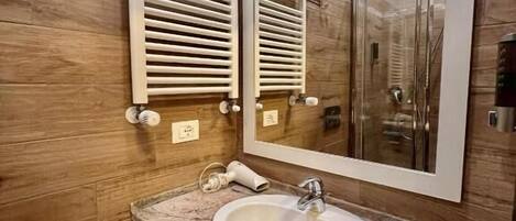 A modern bathroom with a granite countertop sink, a large mirror, and wooden paneling.