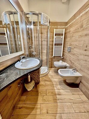 Un baño moderno con ducha, dos lavamanos y un bidé.