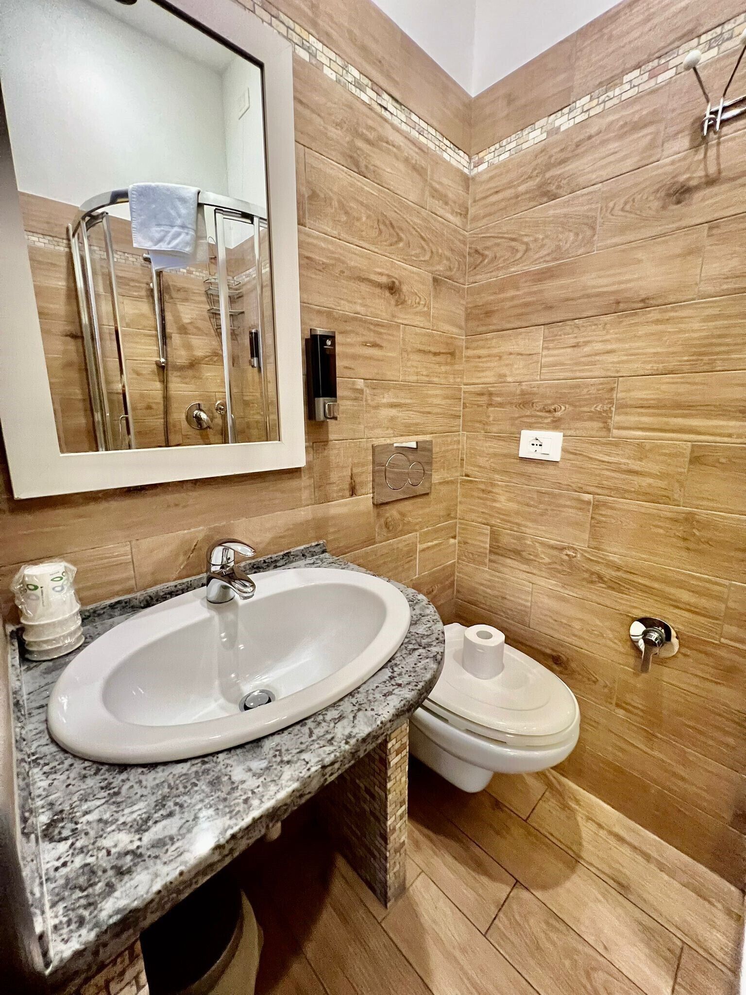 Un baño con lavamanos de mármol, inodoro y ducha.