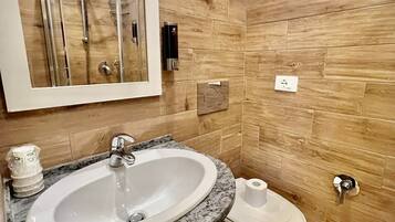 Un baño con lavamanos de mármol, inodoro y ducha.