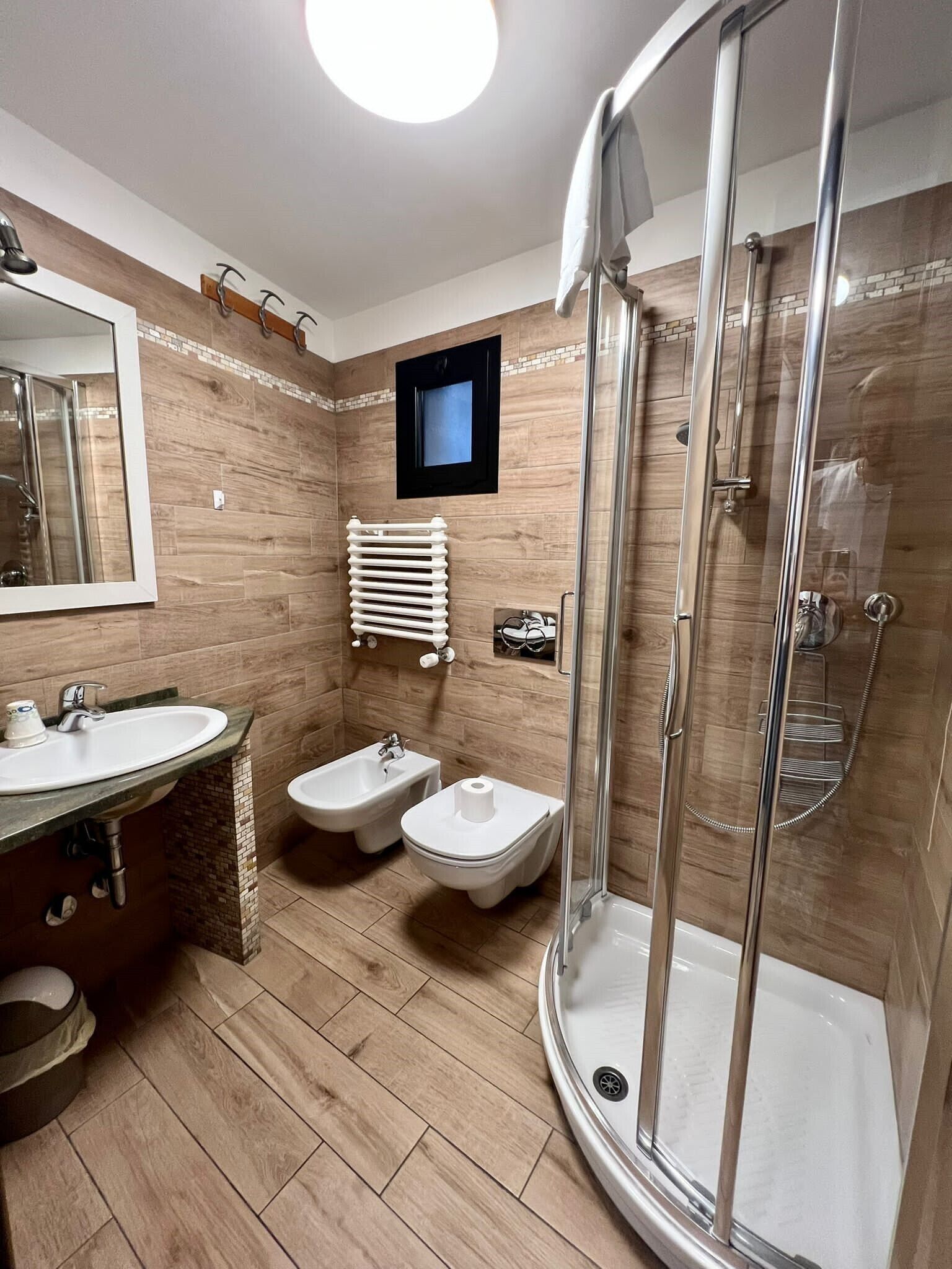 Un baño moderno con ducha, bidé, lavabo y espejo.