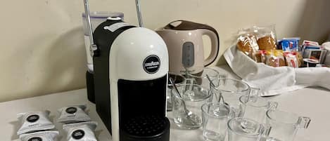 A coffee maker, a mug, and several glass cups on a table.