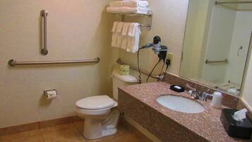 A bathroom with a toilet, sink, handrails, towels, and a hairdryer.