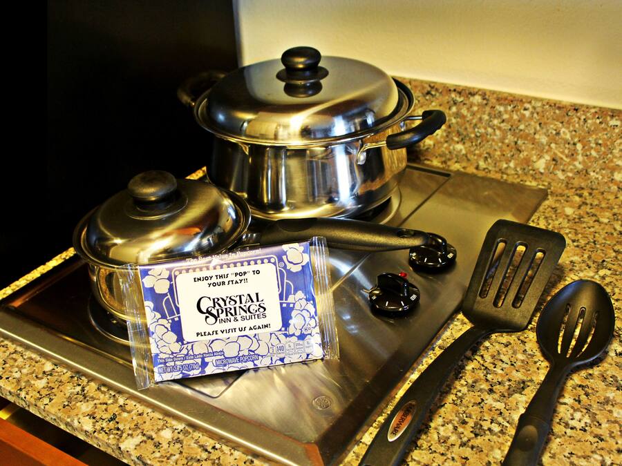 Une cuisine équipée d’appareils électroménagers en acier inoxydable, notamment une cuisinière, des casseroles et une spatule.