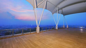 An open terrace with a wooden floor and a view of the cityscape at dusk. - The Alts Hotel (Palembang)