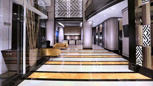 A modern hotel lobby with a black and white striped floor, a reception desk, and a seating area with a sofa. - The Alts Hotel (Palembang)