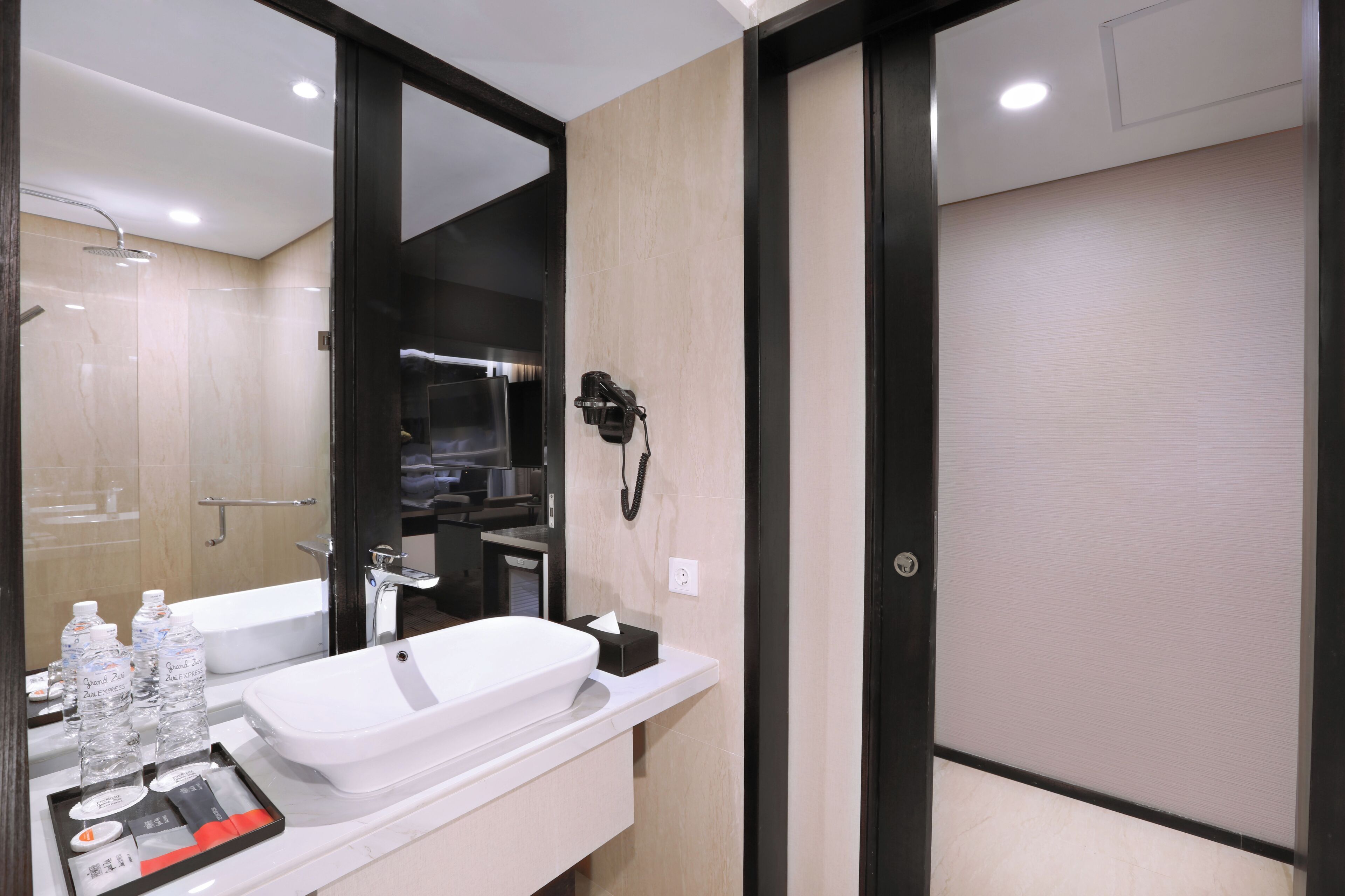 A modern bathroom with a large mirror, a bathtub, a shower, and a hairdryer mounted on the wall.