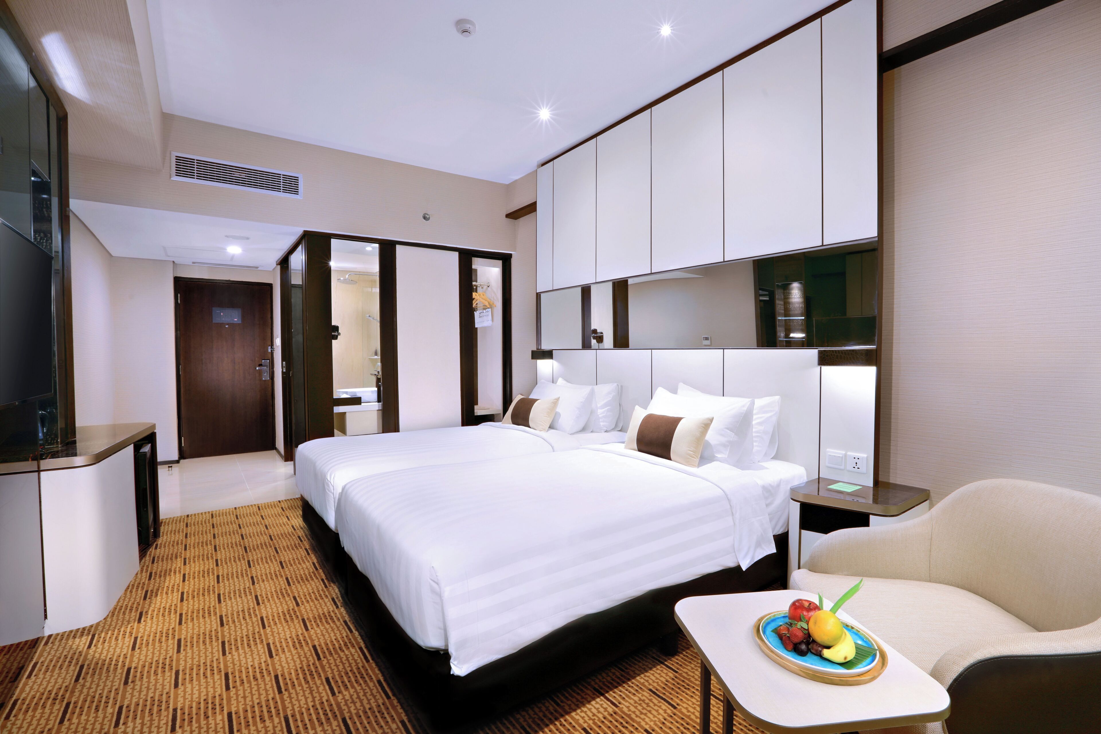Une chambre d’hôtel avec un grand lit, un coin salon avec une petite table et une armoire.