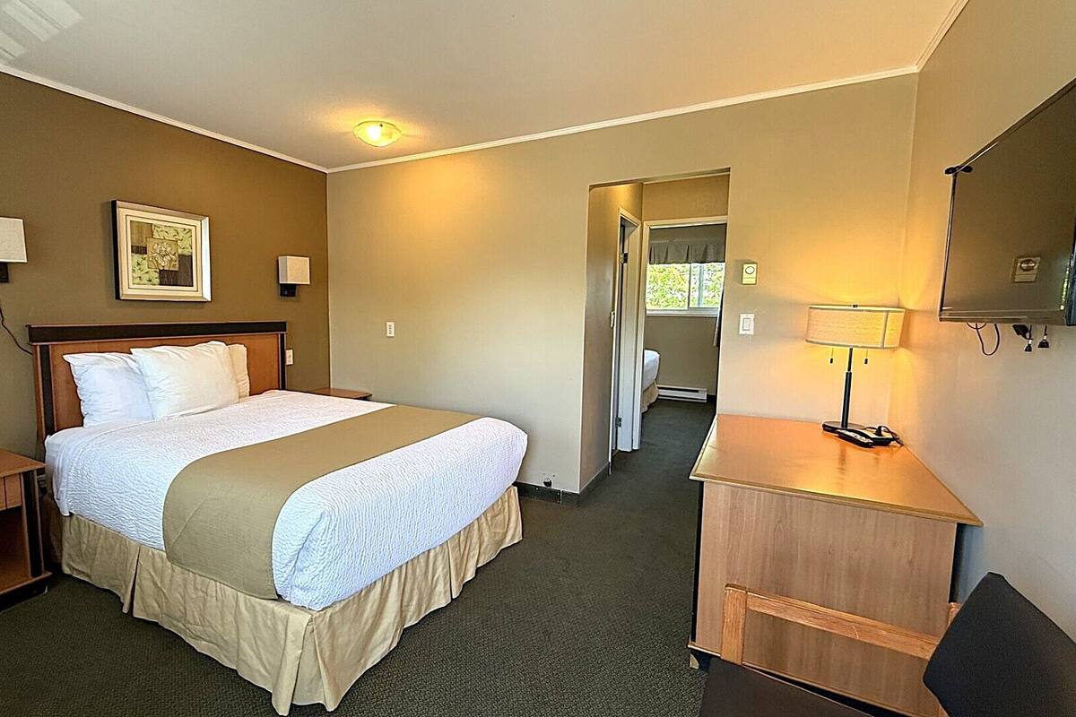 Una habitación de hotel con cama, mesita de noche, lámpara y espejo.