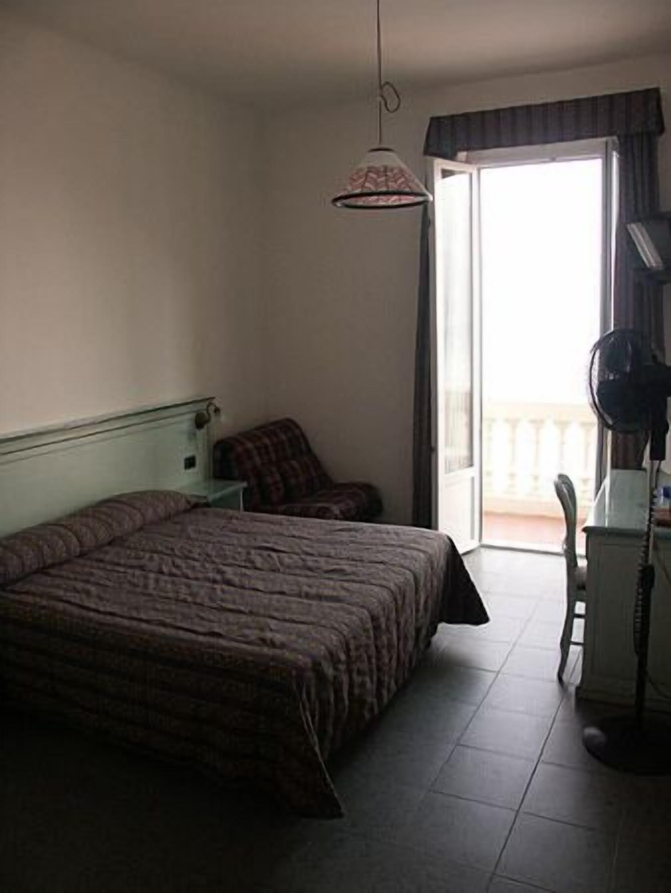 Una habitación de hotel con una cama, un escritorio con teléfono y una ventana que da a vistas del exterior.