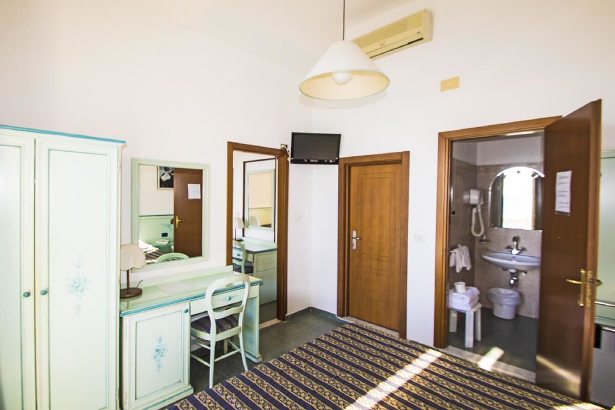 A room with a desk, chair, and a television. There is a bathroom with a sink and a shower.