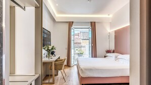 Une chambre d’hôtel moderne dotée d’un grand lit, d’un bureau avec une chaise et offrant une vue sur l’extérieur grâce à une porte vitrée.